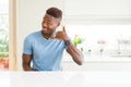 Handsome african american man wearing casual t-shirt at home smiling doing phone gesture with hand and fingers like talking on the Royalty Free Stock Photo