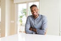 Handsome african american man on white table happy face smiling with crossed arms looking at the camera Royalty Free Stock Photo