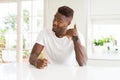 Handsome african american man on white table at home smiling doing phone gesture with hand and fingers like talking on the Royalty Free Stock Photo