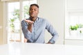 Handsome african american man on white table looking at the camera blowing a kiss with hand on air being lovely and sexy Royalty Free Stock Photo