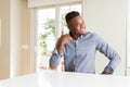 Handsome african american man on white table smiling doing phone gesture with hand and fingers like talking on the telephone Royalty Free Stock Photo