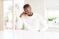 Handsome african american man on white table smiling doing phone gesture with hand and fingers like talking on the telephone Royalty Free Stock Photo