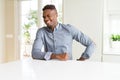 Handsome african american man on white table winking looking at the camera with sexy expression, cheerful and happy face Royalty Free Stock Photo