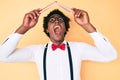 Handsome african american nerd man with afro hair holding book over head angry and mad screaming frustrated and furious, shouting