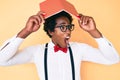 Handsome african american nerd man with afro hair holding book over head angry and mad screaming frustrated and furious, shouting