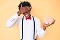 Handsome african american nerd man with afro hair holding brain stressed and frustrated with hand on head, surprised and angry Royalty Free Stock Photo