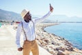 Handsome african american person casual fashion look outfit in straw hat,white shirt walking by Tyrkey coast making Royalty Free Stock Photo