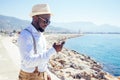 Handsome african american person casual fashion look outfit in straw hat,white shirt walking by Tyrkey coast and using Royalty Free Stock Photo