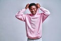 A handsome african american smiling in pink sunglasses is wearing a pink hoodie and is putting on a hood posing for the camera in Royalty Free Stock Photo
