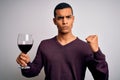 Handsome african american sommelier man tasting glass of red wine over white background annoyed and frustrated shouting with Royalty Free Stock Photo