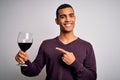 Handsome african american sommelier man tasting glass of red wine over white background very happy pointing with hand and finger Royalty Free Stock Photo