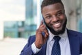 Handsome african businessman in suit speaking on the phone outdoors. Copy space