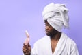 Handsome african man in bathrobe and towel looking at pink small mirror Royalty Free Stock Photo