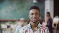 Handsome african man at busy modern office. Portrait of young successful male looking at camera and smiling. Royalty Free Stock Photo