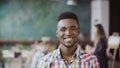 Handsome african man at busy modern office. Portrait of young successful male looking at camera and smiling.