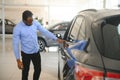 Handsome African man choosing a new car at the dealership Royalty Free Stock Photo