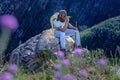A Young African male hiking in the mountains amongst pink fynbos flowers during spring time in South Africa