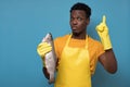 Handsome african serious guy in yellow apron holding in hand big fresh fish