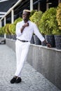 Handsome young Afro American business man wearing stylish clothes in modern city sits near the building Royalty Free Stock Photo