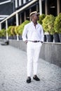 Handsome young Afro American business man wearing stylish clothes in modern city sits near the building Royalty Free Stock Photo