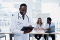 Handsome Afro American doctor in white coat is looking at camera and smiling. Young medical student with a stethoscope Royalty Free Stock Photo