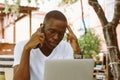 Handsome afro american man with glasses sitting at table in cafe on summer veranda, talking on telephone with closed Royalty Free Stock Photo