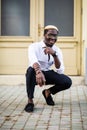 Handsome Afro American man wearing casual clothes in modern city sitting near the building Royalty Free Stock Photo