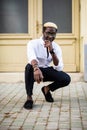 Handsome Afro American man wearing casual clothes in modern city sitting near the building Royalty Free Stock Photo