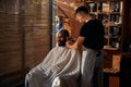 Male barber in apron trimming client beard in barbershop Royalty Free Stock Photo