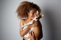 Handsome american african female with afro hair hugging and kissing her puppy basenji dog. Love between dog and owner Royalty Free Stock Photo