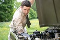 Handsome American WWII GI Army Officer In Uniform And Rolled Up Sleeves Next To Broken Down Willy Jeep