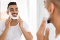 Handsome Arab Man Applying Shaving Foam On Face Near Mirror In Bathroom Royalty Free Stock Photo