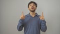 Handsome arab man with beard pointing upwards while standing against a white background Royalty Free Stock Photo