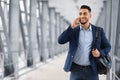 Handsome arab man talking on cellphone while walking with backpack in airport Royalty Free Stock Photo