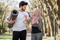 Active arabian guy drinking water while woman using mobile