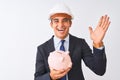 Handsome architect man wearing helmet holding piggy bank over isolated white background very happy and excited, winner expression Royalty Free Stock Photo