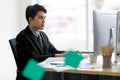 A handsome asian business man wearing formal black suit and necktie, seriously typing and using computer for working with Royalty Free Stock Photo