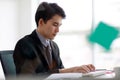 A handsome asian business man wearing formal black suit and necktie, seriously typing and using computer for working with Royalty Free Stock Photo