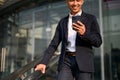 Handsome Asian businessman holding his smartphone while walking down the stairs in a city Royalty Free Stock Photo