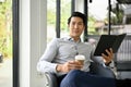 Handsome Asian businessman sits in an office lounge with his notebook and coffee cup Royalty Free Stock Photo