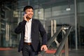 Handsome Asian businessman talking on the phone while walking down the stairs in a city Royalty Free Stock Photo