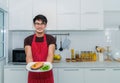 Handsome asian chef standing smiling holding salmon steak in dish