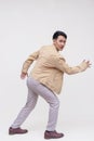 A handsome asian dude in a khaki jacket, white shirt and light gray pants. Making an escape, running pose. Whole body photo, Royalty Free Stock Photo