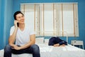 Husband secretly talks on the phone while his wife sleeps.