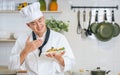 Handsome Asian male chef wearing uniform, holding plate of spaghetti, smiling, smelling with happiness. Restaurant, Food Concept Royalty Free Stock Photo