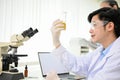 Handsome Asian male scientist in gown and goggles holding a Erlenmeyer flask Royalty Free Stock Photo