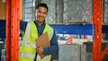 Handsome Asian male warehouse worker in uniform holding a clipboard paper, in warehouse Royalty Free Stock Photo