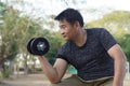 Handsome Asian man exercises outdoor, lift dumbbell. Royalty Free Stock Photo
