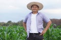 Handsome Asian man farmer is at garden, wears hat, put arms on wais