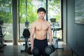 The handsome asian man is holding dumbbells with both hands while standing and looking at the camera at the fitness center Royalty Free Stock Photo